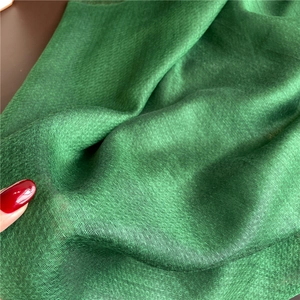 Macro detail of dark green silk scarf fabric showing glossy texture and smooth weave