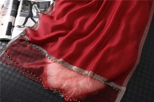 Detail of red silk scarf showing beaded mesh edge and sheer texture on plush fabric