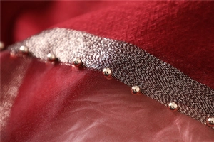 Detailed close-up of dark red silk wool scarf featuring gold bead accents and silver trim