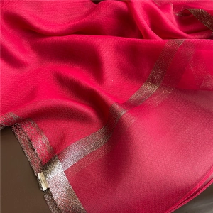 Detail of rose red silk scarf featuring fine horizontal texture and gold metallic borders
