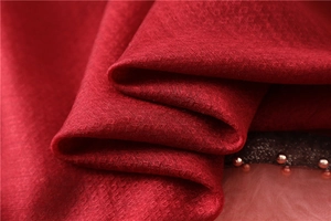Macro view of dark red jacquard silk scarf texture with delicate bead detailing