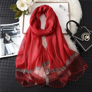 Detail of red silk scarf with silver edge stitching and sparkling bead embellishments