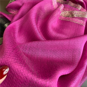 Close-up of silk wool scarf showing magenta texture with circular patterns and gold thread