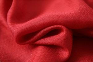 Macro detail of red silk-wool fabric showing cross-weave texture and premium beaded edge