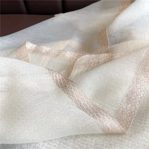 Close-up of lightweight off-white silk shawl featuring gold diamond weave pattern edge