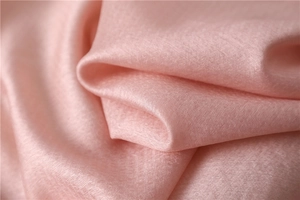 Detailed macro view of soft pink silk fabric with subtle twill texture and satin gloss