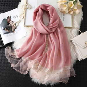 Detailed close-up of pink silk scarf with mesh border and luxury pearl bead embellishments