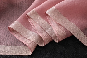 Close-up of pink shawl fabric with vertical pleats and metallic geometric trim details
