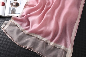 Detail of pink silk shawl with gold beaded edges showing fabric texture and sheen