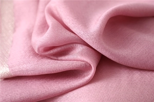 Macro view of pink silk scarf fabric featuring elegant diamond texture and refined piping