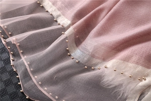Detail of dusty rose scarf with intricate beaded embroidery and soft feather edging
