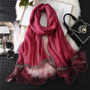 Close-up of wine red scarf with beaded mesh trim and elegant champagne beads detail