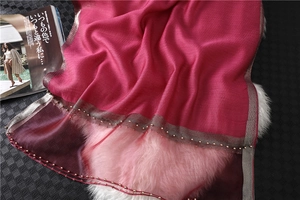 Macro view of rose red silk scarf featuring gold bead trim and metallic woven edges