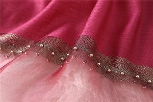 Detail of pink silk scarf featuring wavy lace edges and delicate gold beadwork decor