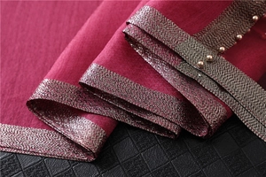 Detail of rose pink silk shawl featuring silver-red metallic trim and golden bead accents