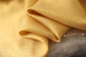 Macro detail of yellow silk scarf fabric with fine jacquard patterns and luxury texture