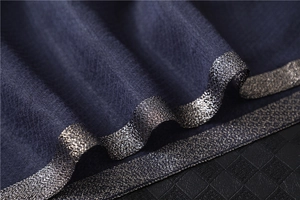 Macro view of dark blue silk scarf featuring silver metallic threads and jacquard texture