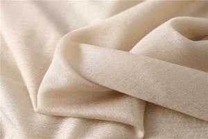 Detailed view of champagne silk scarf fabric with elegant texture and soft pearlescent glow