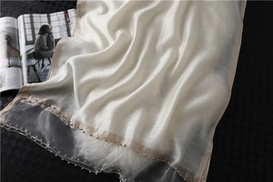 Detail of ivory silk shawl with elegant champagne gold bead trim on fabric edge