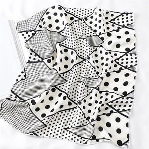 Detailopname van zwart-witte satijnen sjaal met polkadots en gladde zijdeachtige textuur