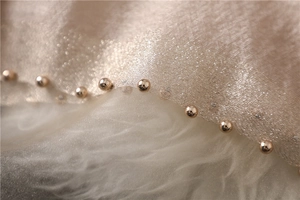Detail of champagne gold glitter scarf featuring decorative beaded edges and sheer fabric