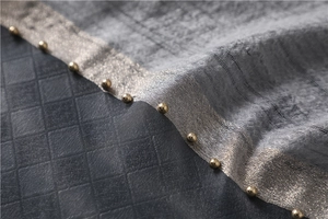 Macro detail of grey textured silk scarf featuring delicate gold beads and sheer edging