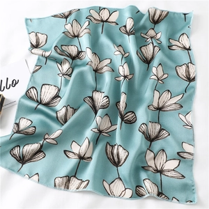 Detail van een mintgroene satijnen sjaal met witte bloemenpatronen en premium stiksels
