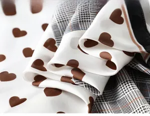 Detailed view of silk satin scarf featuring houndstooth pattern and brown heart prints