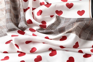 Close-up of silk-like scarf featuring heart prints, houndstooth patterns, and soft texture