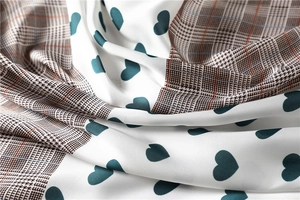 Macro shot of satin silk scarf featuring heart prints and classic plaid texture details