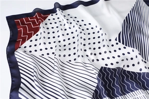 Detail of silk-like scarf with navy and burgundy geometric patterns and satin finish