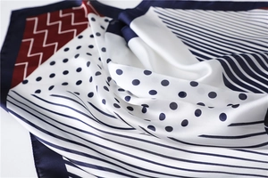 Detailed close-up of navy blue and burgundy geometric silk scarf with stripes and polka dots