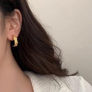 Close-up of gold bamboo-style hoop earring with micro-pave cubic zirconia on model