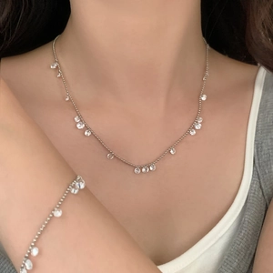 Detailed view of silver zircon drop necklace and matching bracelet set on model neck