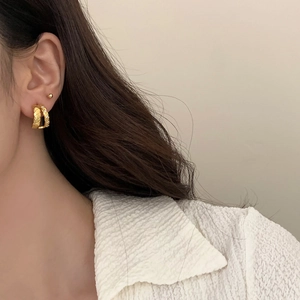 Detail of gold-plated double-layer C-shaped hoop earrings with quilted texture and zircons