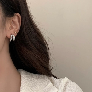 Detail of silver C-shaped earrings with diamond pattern texture on fashion model