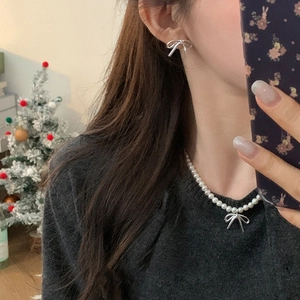 Detail of silver bow earrings and matching pearl necklace on model for gift set