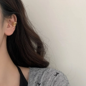 Close-up of a three-layer golden ear cuff with sparkling zircons worn on the ear