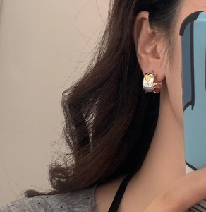 Silver wide hoop earrings with gold 3D heart charms worn on a female model