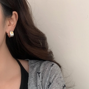 Close-up of vintage silver hoop earring with gold heart worn by model in soft lighting