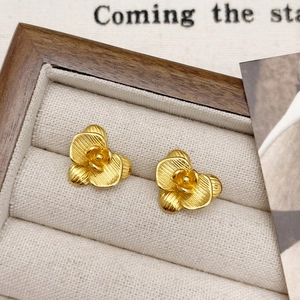 Close-up of golden flower stud earrings with brushed texture in a wooden jewelry box