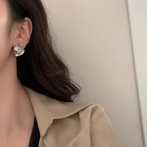 Detailed view of a silver 3D rose stud earring on a model with minimalist styling
