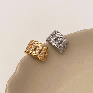 Dettaglio macro di earcuff placcati in oro e argento con micro-pavé di zirconi cubici