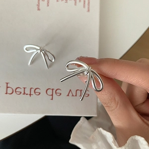 Detailed close-up of elegant silver bow stud earrings with a minimalist metal knot design