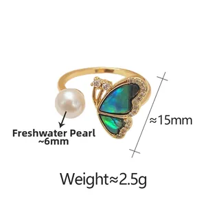 Detail of adjustable gold ring featuring freshwater pearl and blue shell butterfly wings