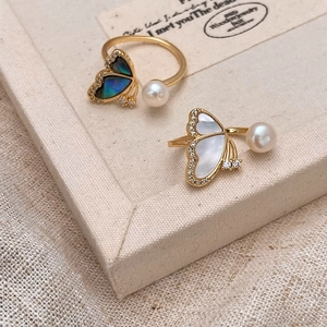 Detailed close-up of shell butterfly rings with freshwater pearls and zircon accents
