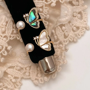 Detail of adjustable gold butterfly rings with freshwater pearls and shell inlays