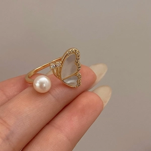 Macro detail of adjustable butterfly ring with mother of pearl and shell heart accents