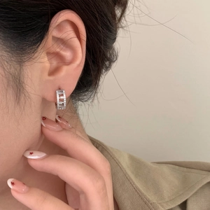 Elegant geometric silver hoop earrings with micro-pave cubic zirconia on a model's ear