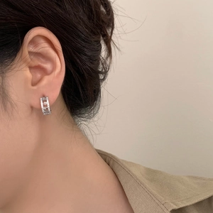 Detail of silver hoop earrings with micro-set zircons on a model for daily wear